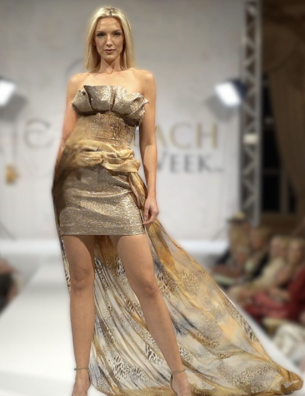 Model walks runway in Birgit C Muller gold lame and Cavalli fabric bustier skirt set with dramatic train at Palm Beach Fashion Week show
